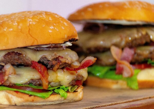Close-up of juicy bacon cheeseburgers topped with fresh lettuce and melting cheese, perfect for fast food lovers.